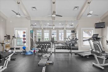 A spacious gym with a variety of equipment including treadmills, weights, and a television. at Somerset Oaks Apartment Homes, Olathe, KS